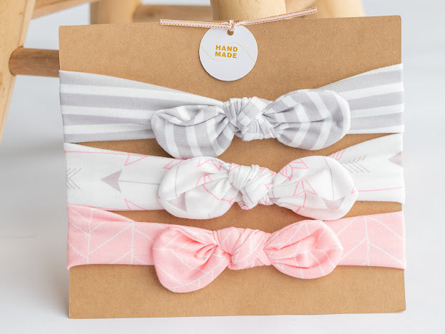 Stretchy grow-with-me set of three coordinating infant headbands with center bow, Gray  and white stripe, pink chevron, white and pink arrow. 