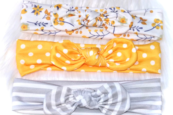 Stretchy grow-with-me set of three coordinating infant headbands with center bow, bright yellow polka dot, gray and white stripe, white and yellow floral.