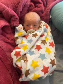 Baby Nash wrapped up in large star pattern muslin swaddle